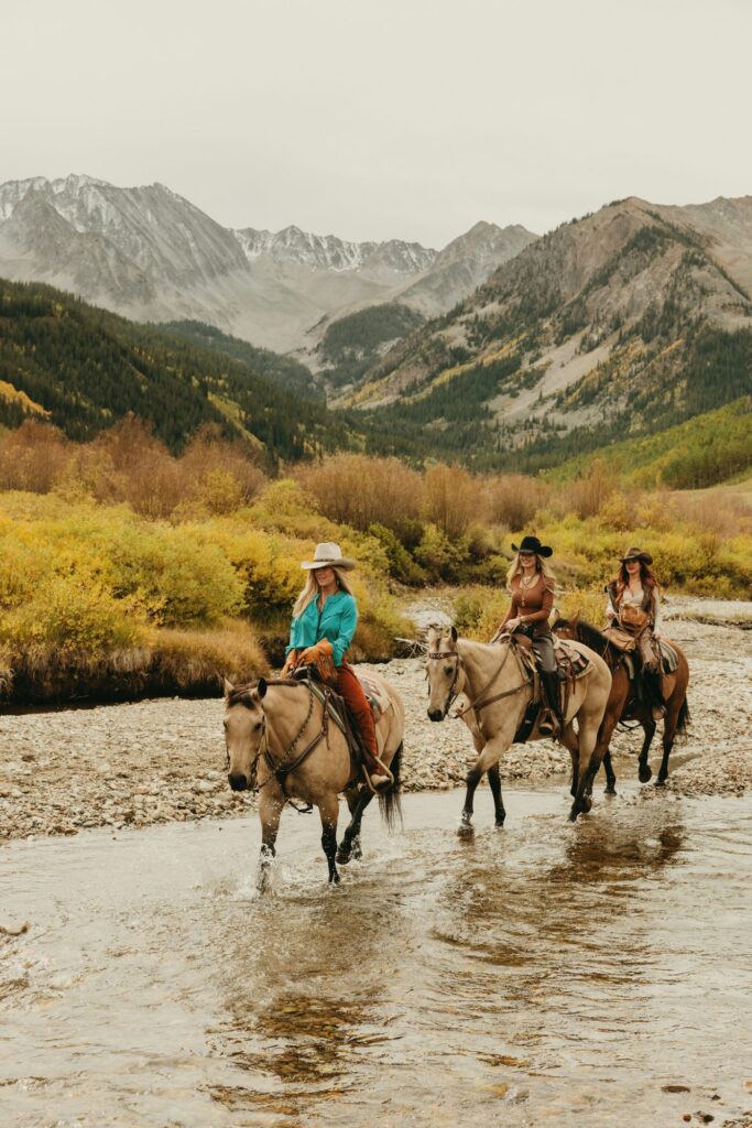 Horseback riders crossing a mountain river in fall