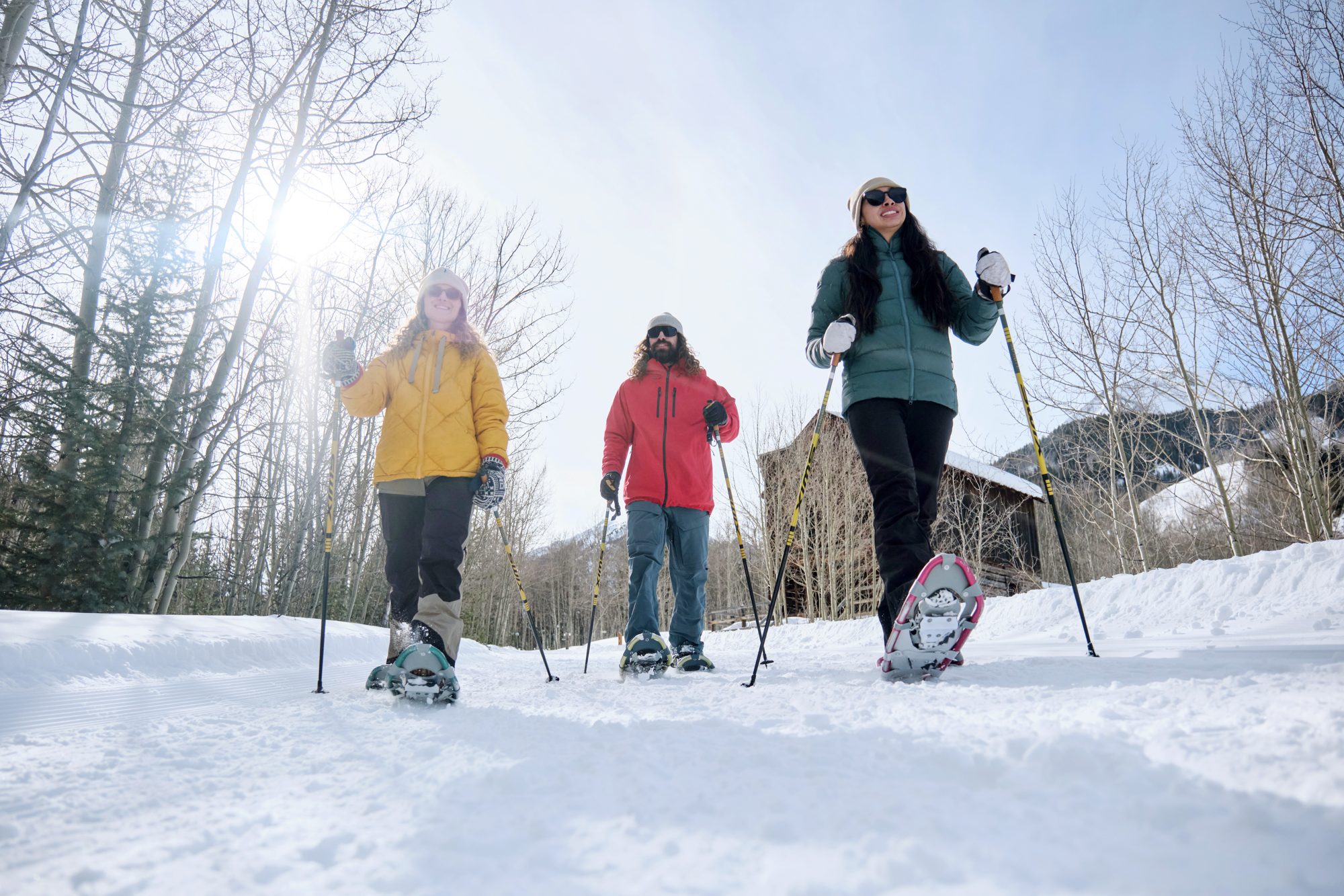 Friends snowshoeing on a sunny winter trail